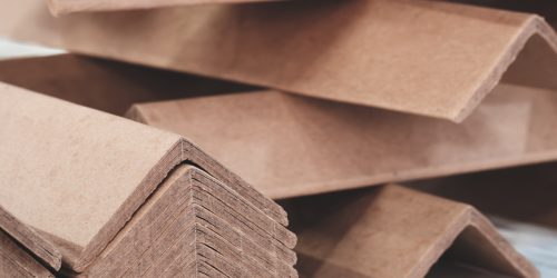 Stack of cardboard corner protectors for packaging, corners are brown and arranged in a row as background templates of pages and banners of delivery logistics concept.